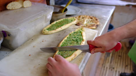 baked pitas are being sliced