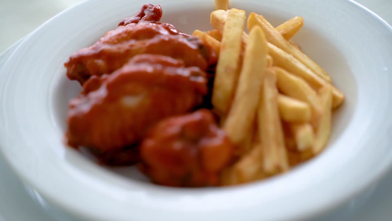 alas de pollo de búfalo con papas fritas servidas en un plato blanco