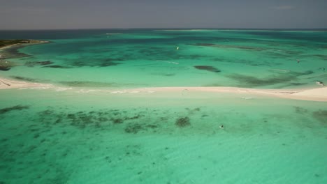 Kitesurfer-Gleitet-An-Einem-Sonnigen-Tag-über-Das-Türkisfarbene-Wasser-Einer-Kleinen-Sandinsel