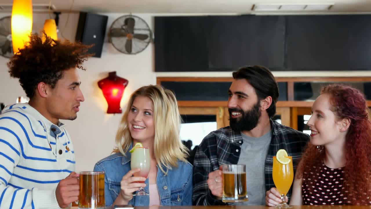 Uomo che fa un brindisi in un pub e amici che fanno
