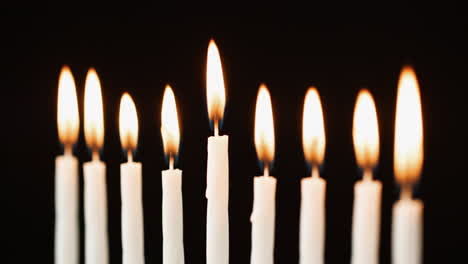 Close up of nine lit candles burning for the Jewish holiday of Hanukkah, selective focus