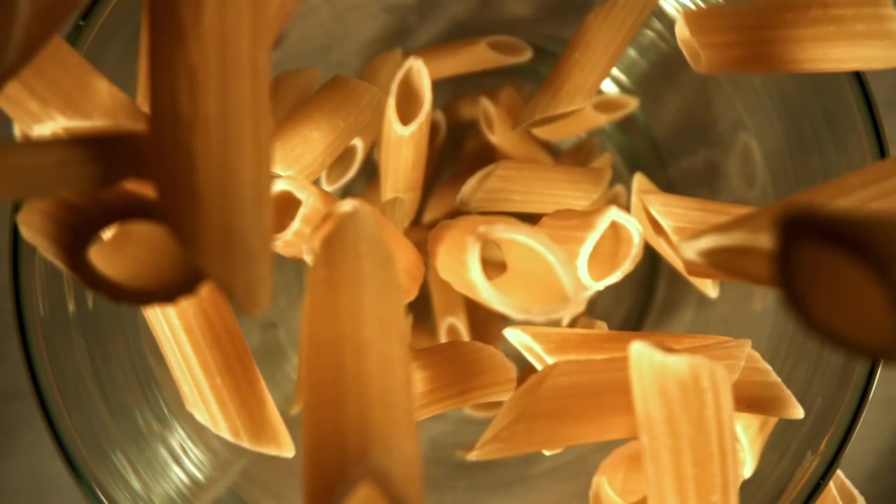 Penne che cadono in una ciotola di vetro al rallentatore