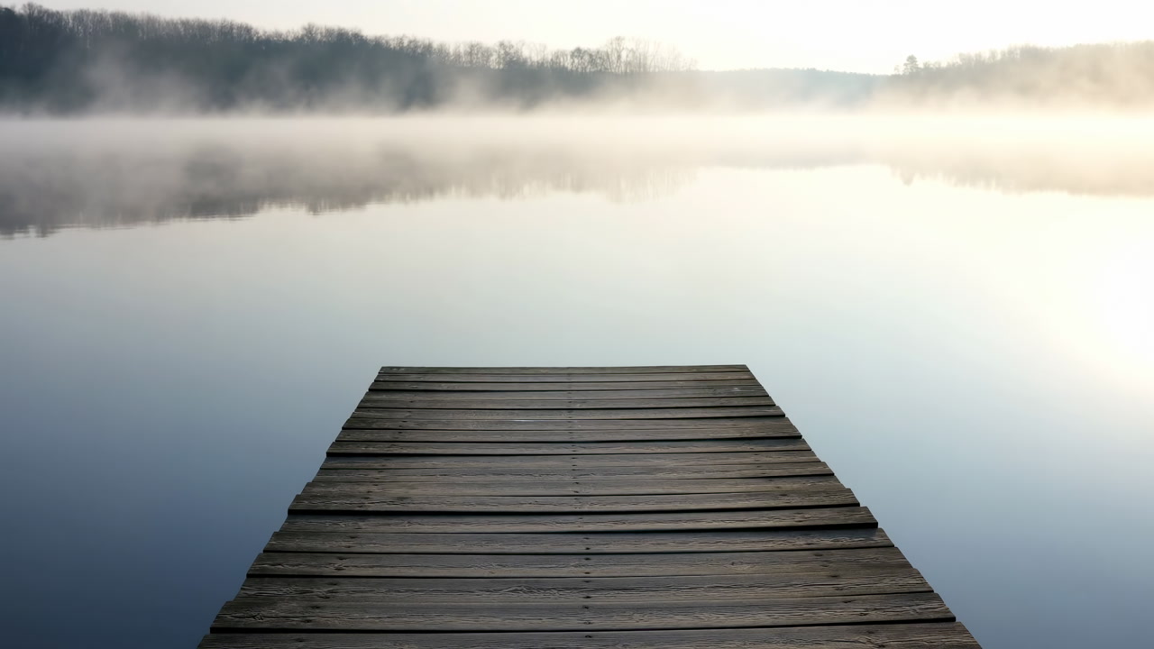 Quiet Misty Dock Over Glassy Lake, Wooden Planks Leading Into Mirrorlike Water, Low Morning Fog Hovering