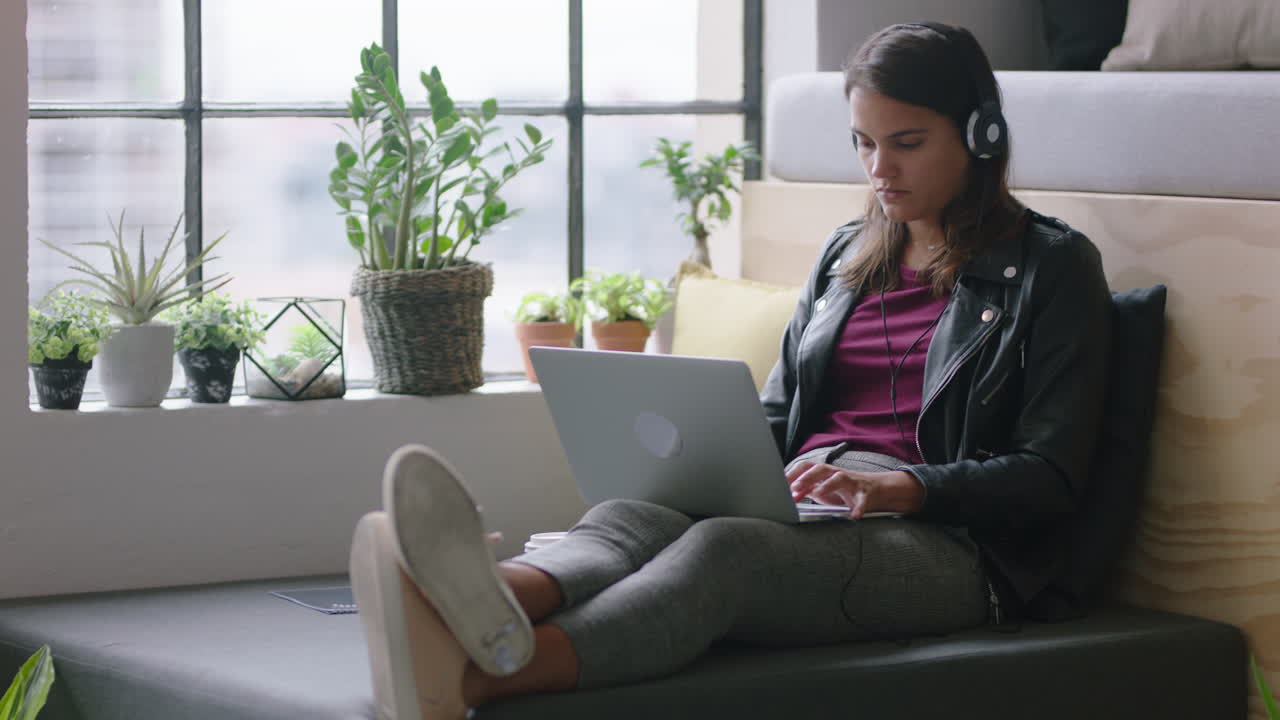 young hispanic business woman using laptop computer student working on project studying typing email messages browsing online networking enjoying listening to music in relaxed office workplace