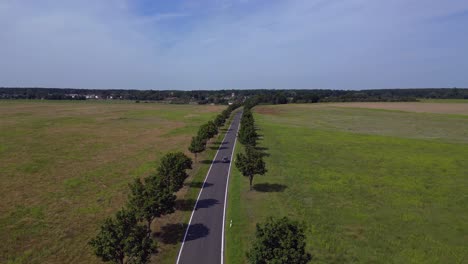 cars driving on a countryside road crossing vast fields under blue sky. nice aerial view flight overflight flyover drone
