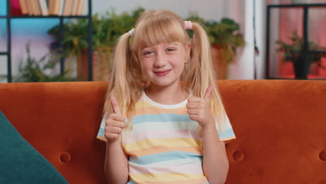 happy child kid girl looking approvingly at camera showing thumbs up like positive sign good news