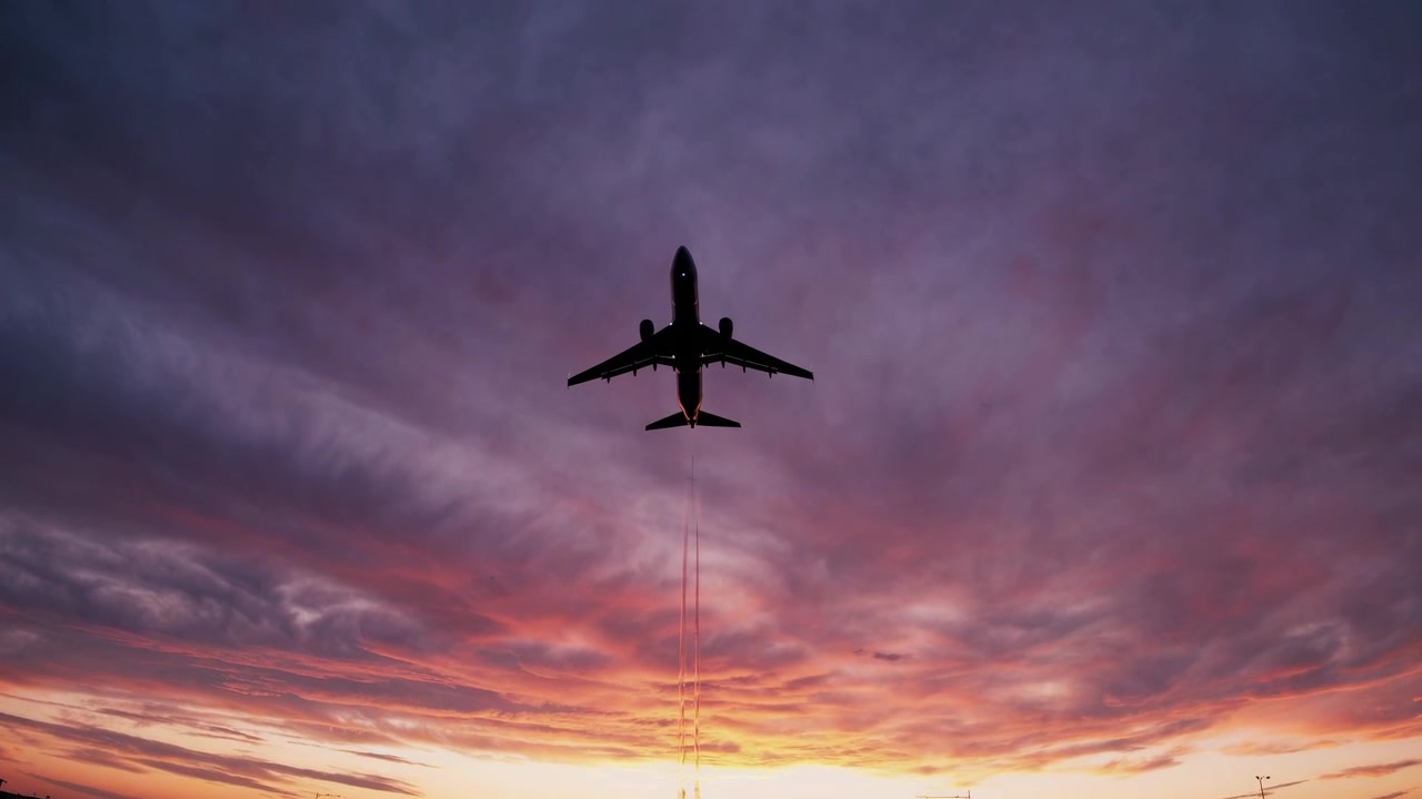 Avión comercial volando contra un vibrante cielo al atardecer