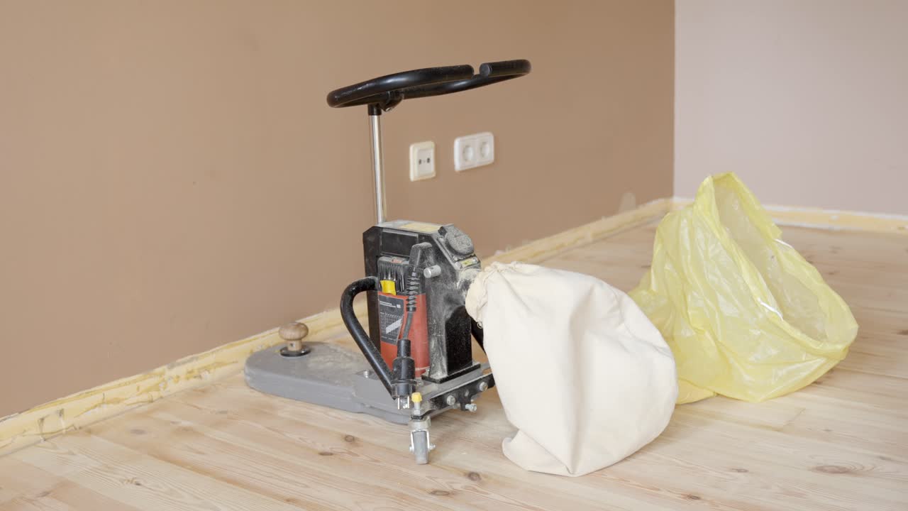 Worker attaching dust bag of floor sanding machine in renovation process