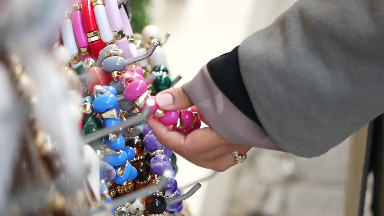 Colorful jewelry display with a hand selecting a bracelet