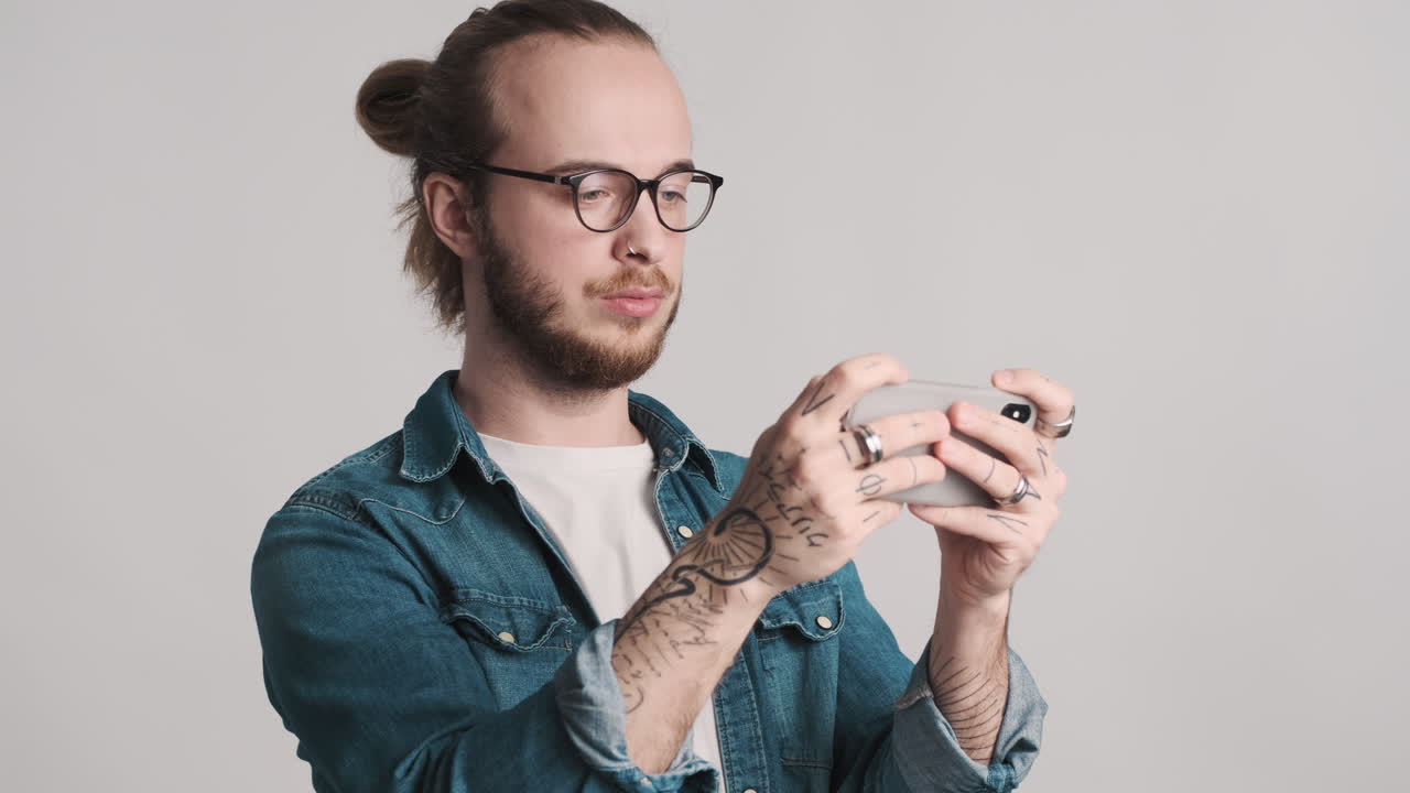 Caucasian young man playing video games on smartphone and winning.