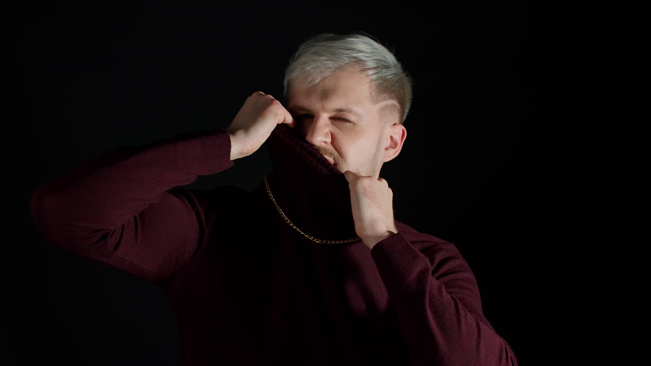 트렌디한 옷을 입은 파란 눈을 가진 세련된 남자가 카메라를 바라보고 행복, 재미, 즐거움을 느니다.