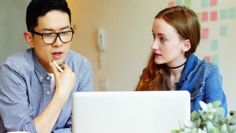 Business-executives-discussing-over-laptop