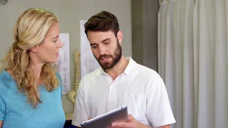 physiotherapist showing digital tablet to woman