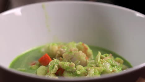 steaming peruvian cilantro seafood soup in bowl - close up, slow motion