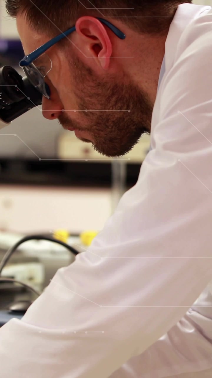 Video verticale: Ricercatore di laboratorio che osserva al microscopio, regolando la messa a fuoco con un'interfaccia HUD in sovrimpressione che assiste l'analisi.