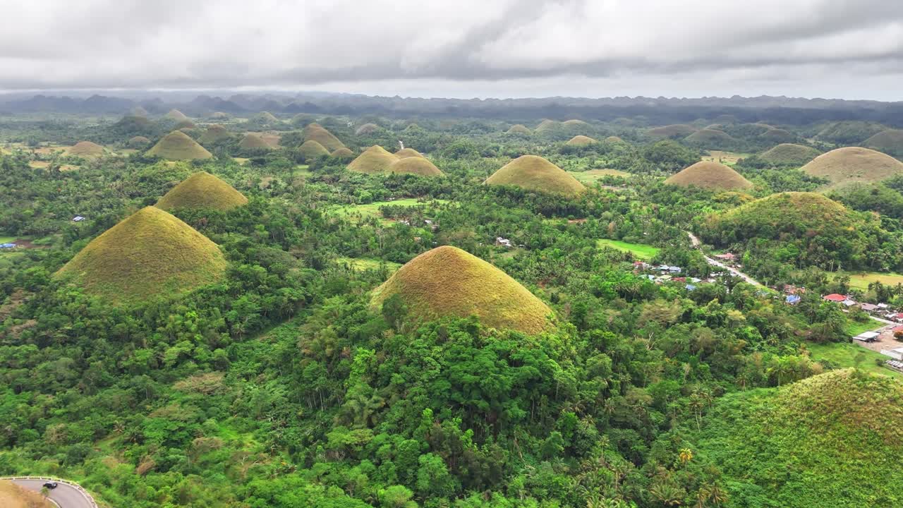 Group of cone-shaped hills emerge from dense green jungle in this high drone view of Chocolate Hills, Bohol, Philippines, showcasing one of the country’s most unique and mysterious formations
