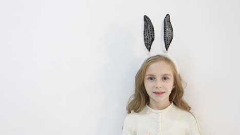 little girl in a cloak, dressed in the ears of an easter bunny, a happy child is waiting for the holidays, on a white background