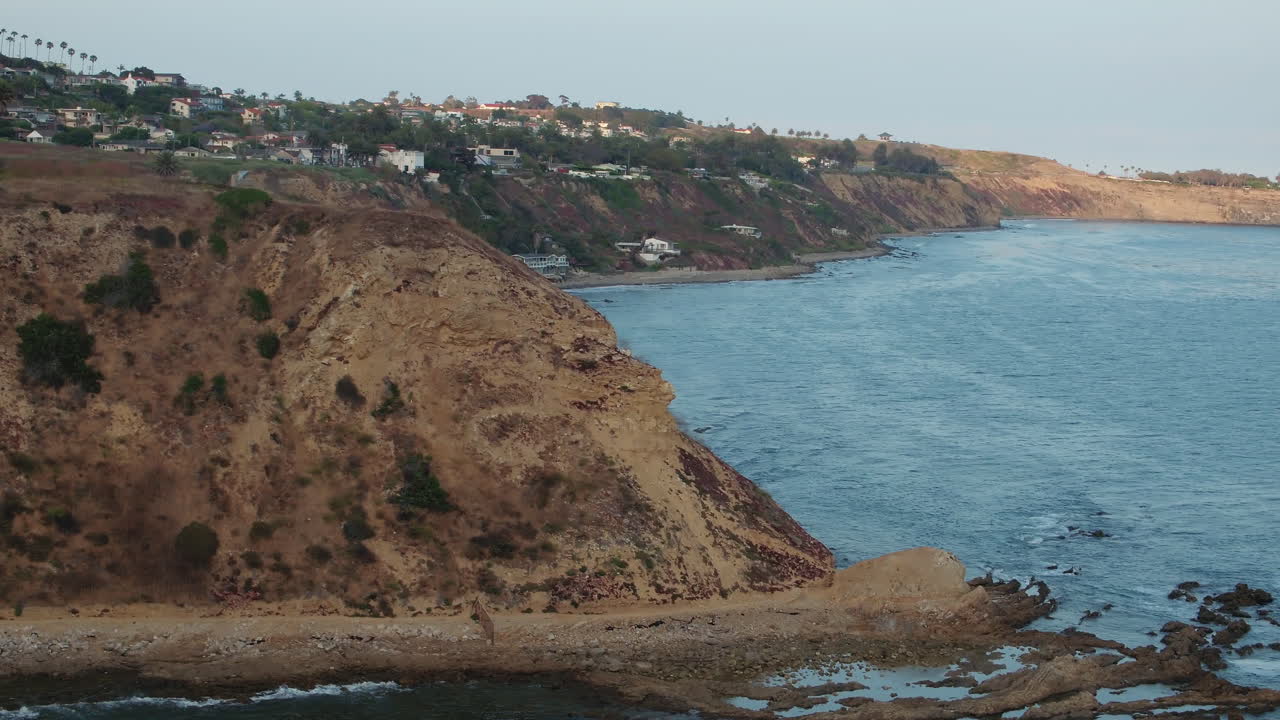 vista aérea de pájaro de arriba hacia abajo de las olas rompiendo en una playa rocosa del sur de california