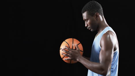 Un-Hombre-Afroamericano-Se-Centra-En-Una-Pelota-De-Baloncesto,-Con-Espacio-Para-Copiar-En-Un-Fondo-Negro.