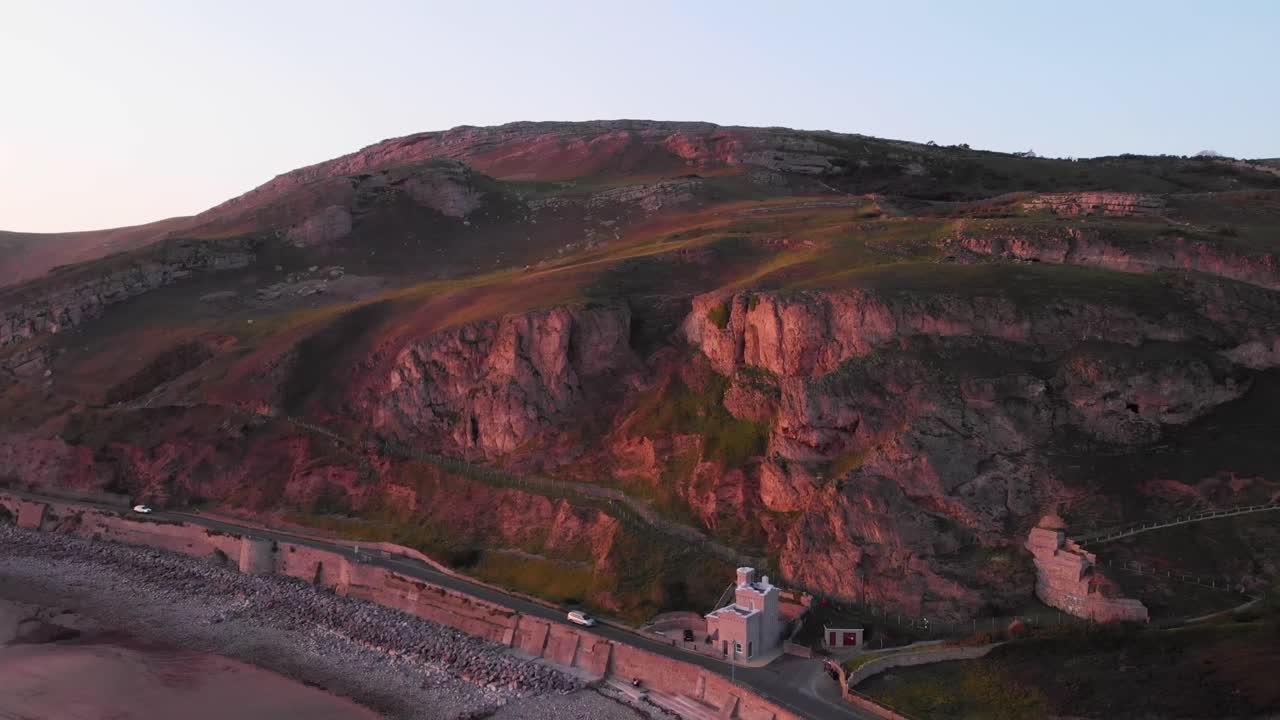 una puesta de sol rosa se refleja en los acantilados de piedra caliza del gran orme en gales, vista aérea