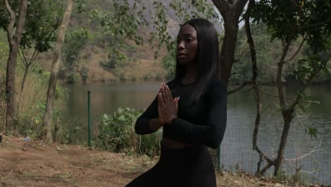 profile shot of a lady in the tree pose by the lake, static medium shot