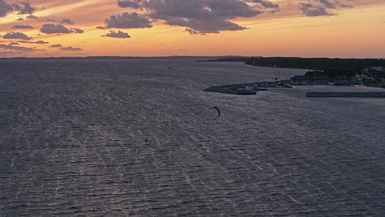 silueta de un hombre en una tabla de cometas en el mar al atardecer, vista aérea