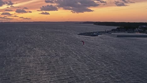 Silueta-De-Un-Hombre-En-Una-Tabla-De-Cometas-En-El-Mar-Al-Atardecer,-Vista-Aérea