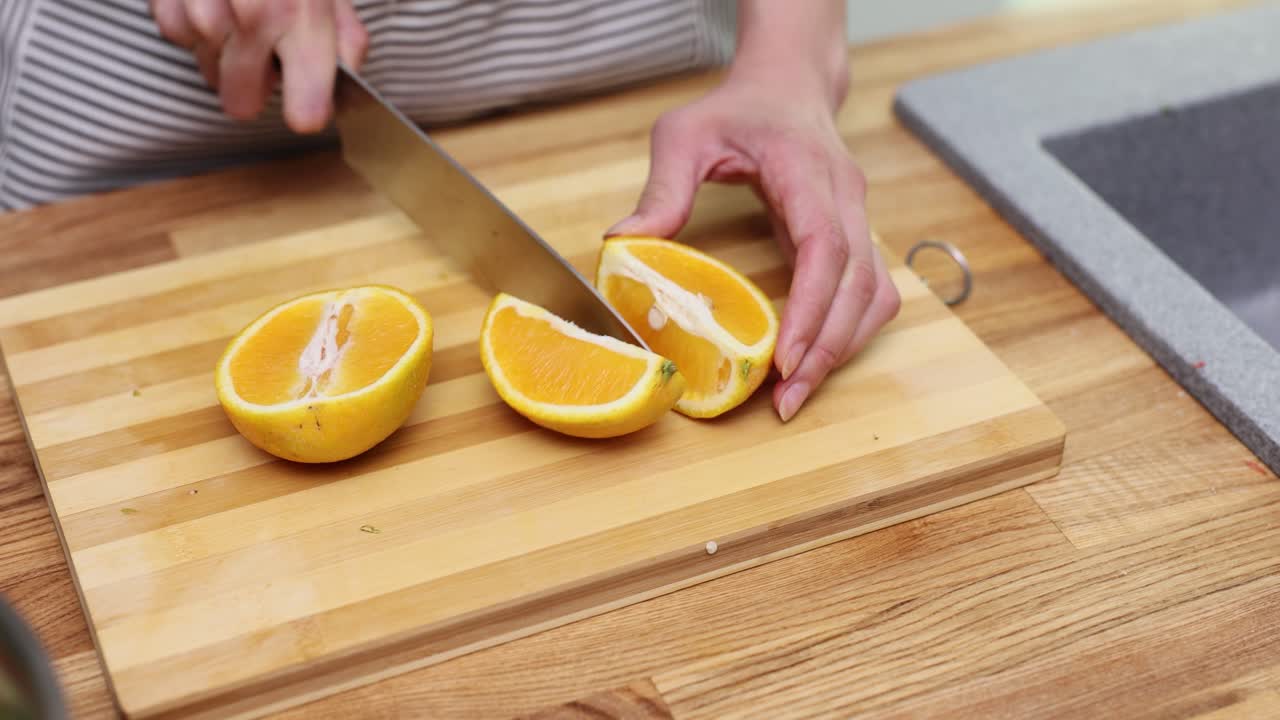 Cutting orange on wooden board