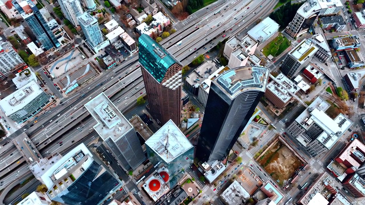 Voando alto sobre o centro de Seattle, Estado de Washington, EUA. Vista aérea dos telhados de arranha-céus e da rodovia de várias pistas com tráfego intenso. Vista aérea.