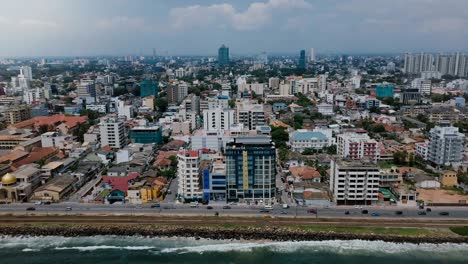 drone zooming out above colombo, sri lanka panorama. aerial view of asian resort town, modern buildings and ocean waves