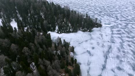 Drone-flight-over-a-frozen-lake-in-the-Engadin-Valley,-Switzerland-during-winter-times