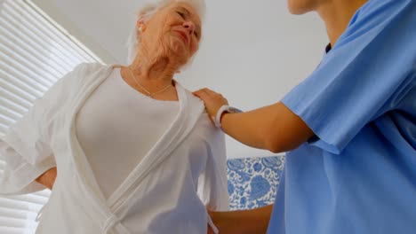 Low-angle-view-of-Caucasian-female-doctor-consoling-senior-woman-at-home-4k