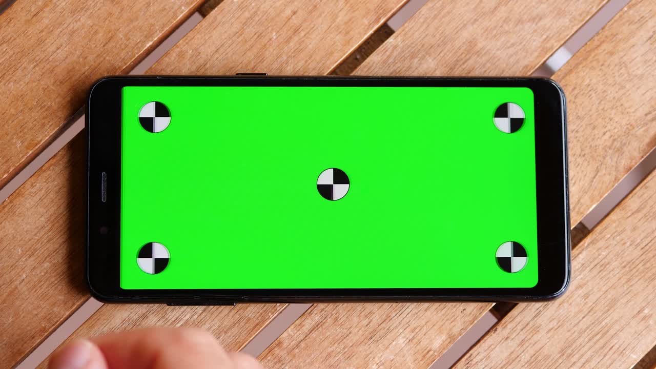 녹색 화면과 마커가 있는 테이블 나무 위에 스마트 폰을 놓습니다.