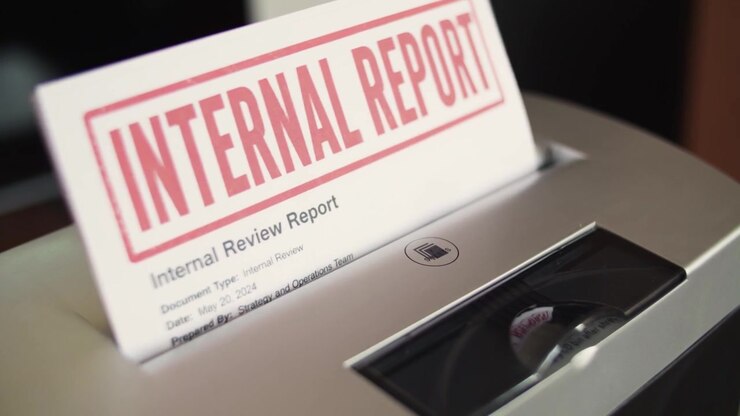 Internal report pages being fed into a paper shredder for office disposal