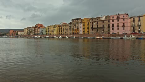 Majestätisches-Dorf-Bosa-Am-Flussufer-In-Sardinien-Mit-Vielen-Booten,-Kameraschwenk-Nach-Rechts