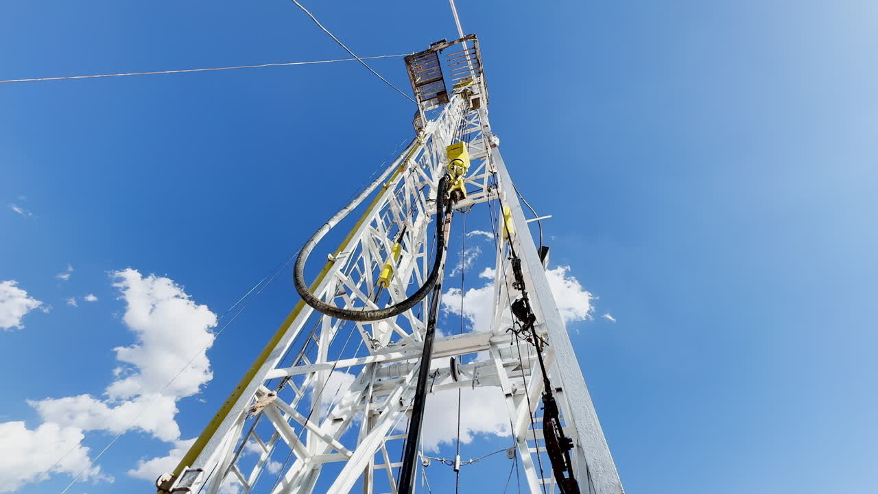 High metal derrick with rotary equipment. Site for natural resources drilling. Low angle view.