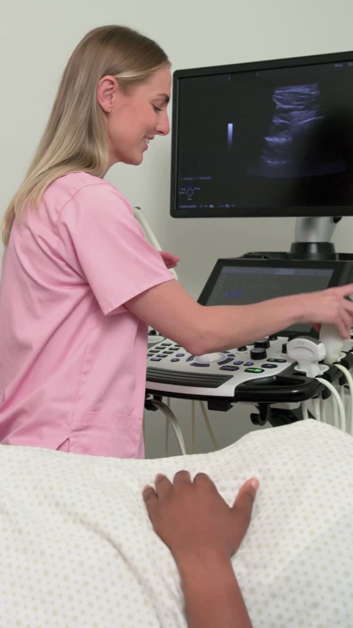 Video verticale: Applicazione di gel, tecnico in camice rosa che posiziona la sonda e scansiona l'addome in clinica per un controllo.