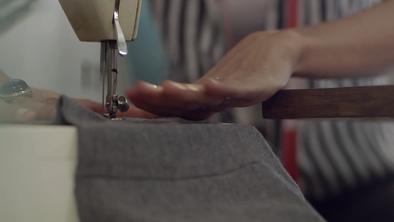 Close Up of Hands Operating a Sewing Machine Stitching Fabric
