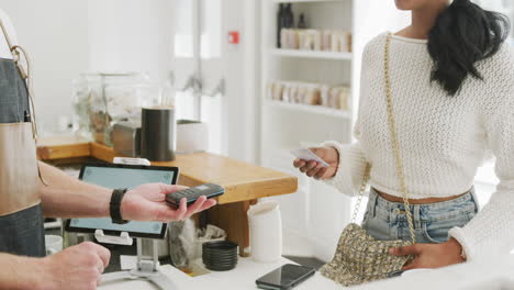 Happy-biracial-woman-paying-caucasian-male-barista-with-credit-card-in-cafe