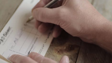 mano escribiendo un cheque bancario para pagar facturas