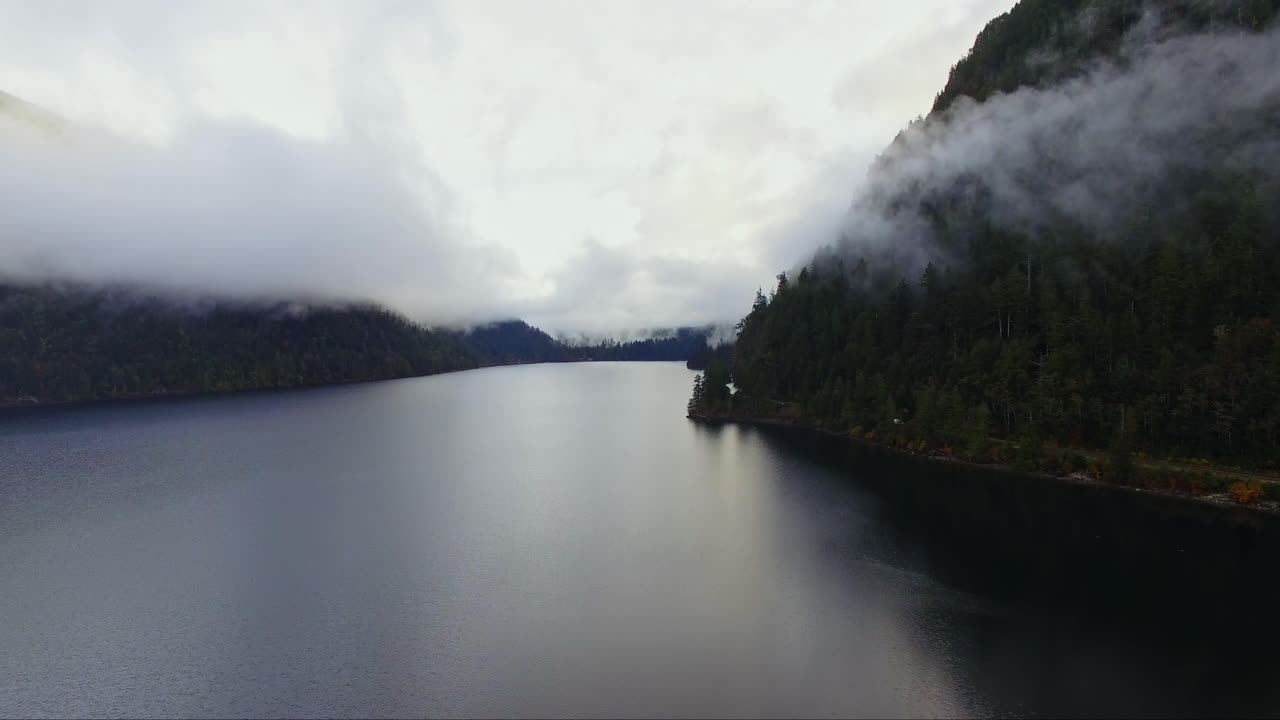 Vista aerea panoramica di un fiume attraverso montagne coperte da nuvole basse, paesaggio costiero selvaggio della Columbia Britannica, Canada