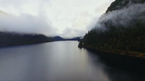 panoramic aerial view of river through mountains covered by low lying clouds, wild coastal landscape of british columbia canada