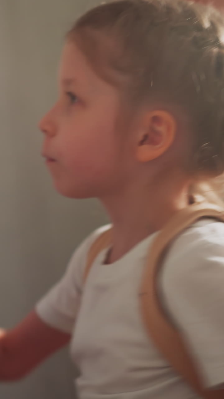Determined girl punches person picture on boxing bag in playing room slow motion. Emotional child expresses anger at fight training in domestic gym