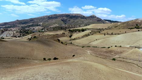 Wide-landscape-view-of-curvy-hills-revealing-distant-road,-aerial-parallax-drone-shot