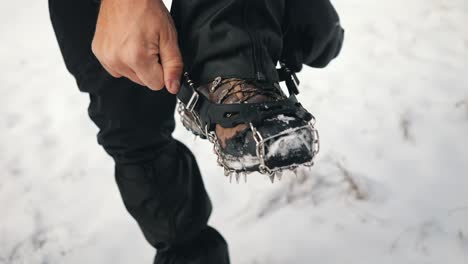 a hiker trying to put crampon on his winter boots