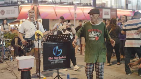 local buskers performing on kuala lumpur streets during nighttime in malaysia. people enjoying.