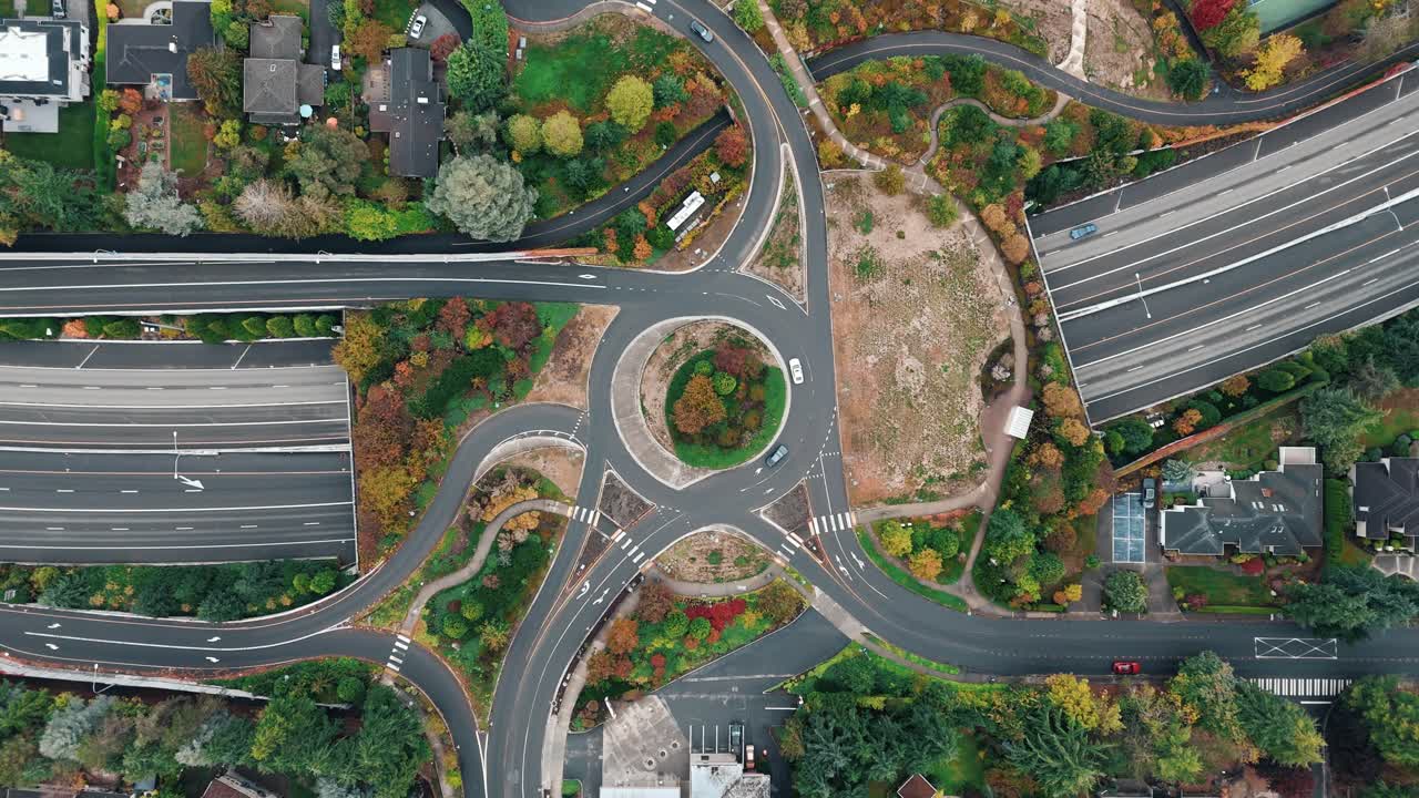 Traffic flows below and above as a fall-colored overpass wraps the freeway