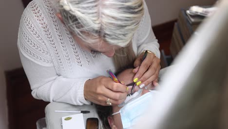 Beautician-applying-eyelashes-on-face-of-woman