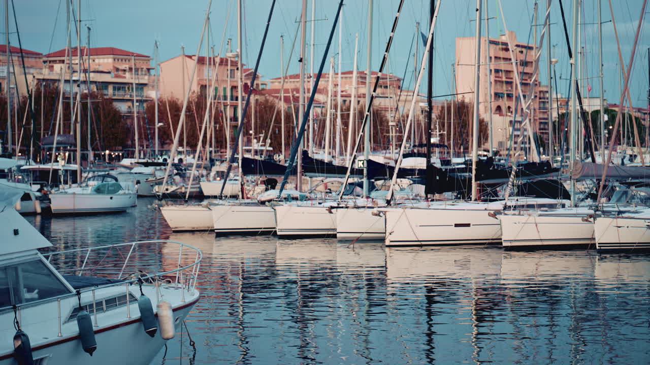 A yacht's bow in the foreground with the marina and boats in the background at blue hour
