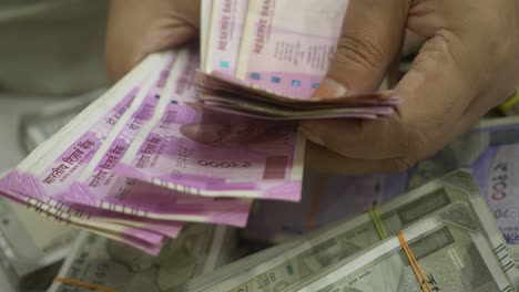 an indian businessman counting a new series of 2000 rupee banknotes, cash in hand, closeup